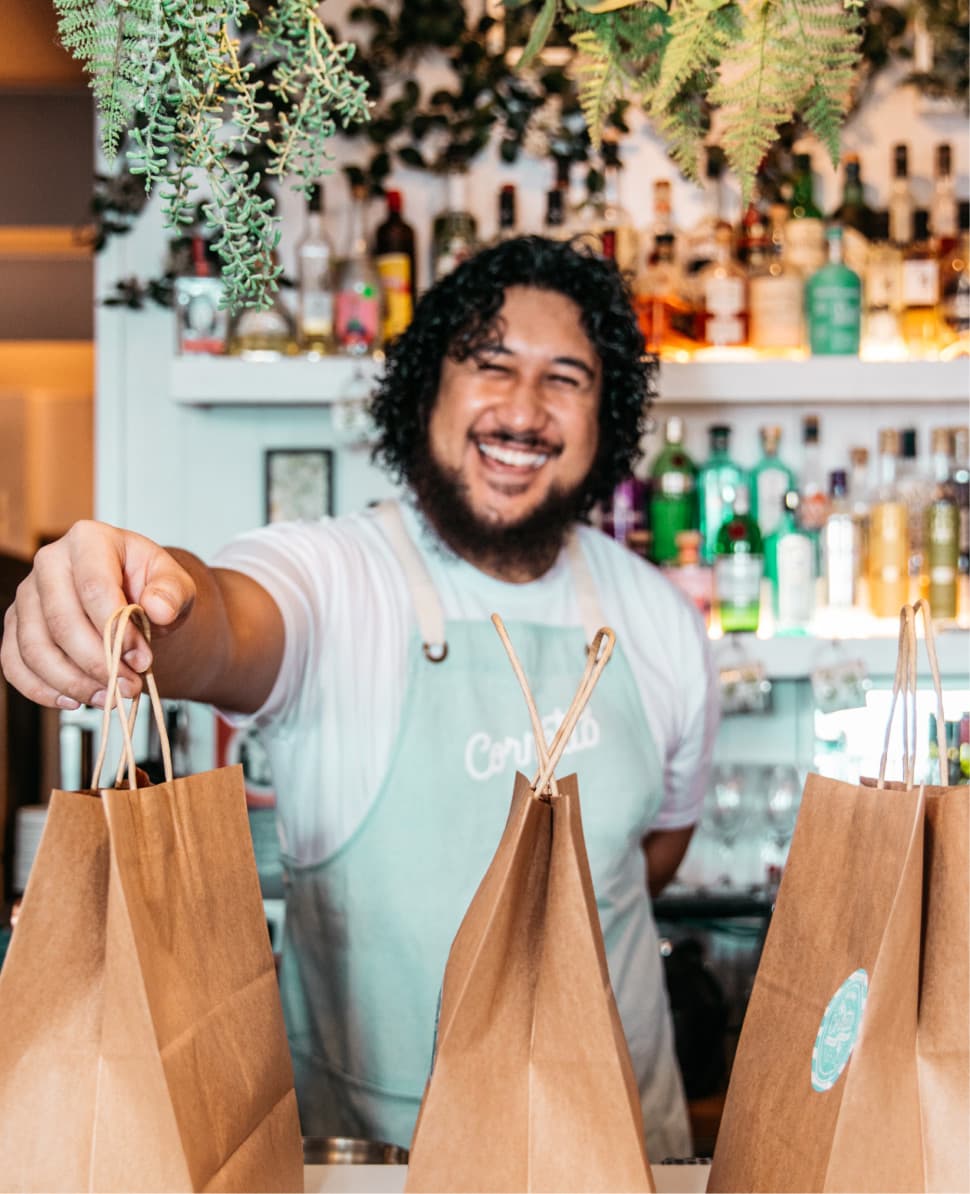 Man smile at counter with takeaway bags lined up